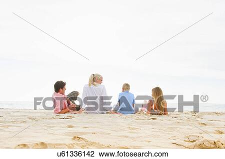 Stock Image - Family sitting on beach. Fotosearch