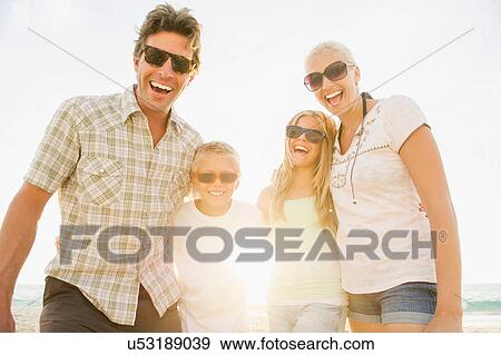 Family smiling at camera with arms around each other View Large Photo Image Stock Photo - Family smiling at camera with arms around each other. Fotosearch