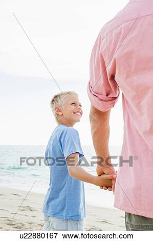Stock Photo - Father and son holding hands on beach. Fotosearch