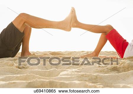 Stock Photography - Father and son on beach touching feet. Fotosearch