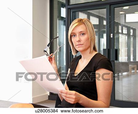 Picture - Female office worker holding glasses and document. Fotosearch