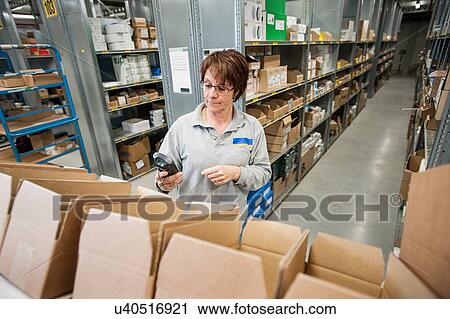 Stock Image - Female warehouse worker checking orders. Fotosearch