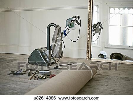 Stock Photograph - Floor sander and rolled up carpet in new home. Fotosearch