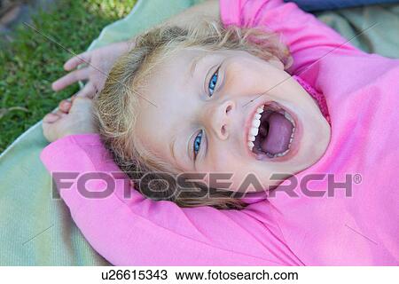Girl lying down with mouth open, smiling View Large Photo Image Stock Image - Girl lying down with mouth open, smiling. Fotosearch