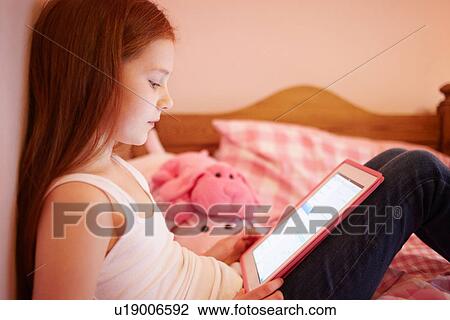 Girl using digital tablet in bedroom View Large Photo Image Stock Image - Girl using digital tablet in bedroom. Fotosearch
