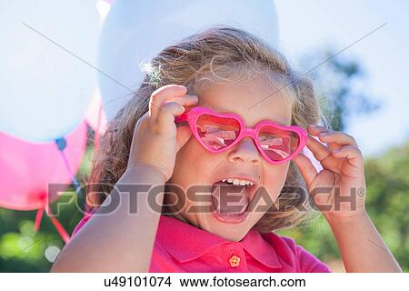 Girl wearing pink heart shaped sunglasses View Large Photo Image Picture - Girl wearing pink heart shaped sunglasses. Fotosearch