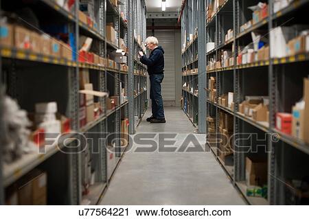 Stock Image - Male warehouse worker searching for item. Fotosearch