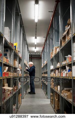 Male warehouse worker selecting item from shelving View Large Photo Image Stock Photo - Male warehouse worker selecting item from shelving. Fotosearch