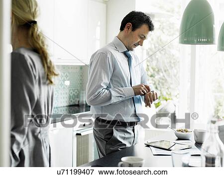 Mature businessman checking time in kitchen View Large Photo Image Stock Photo - Mature businessman checking time in kitchen. Fotosearch