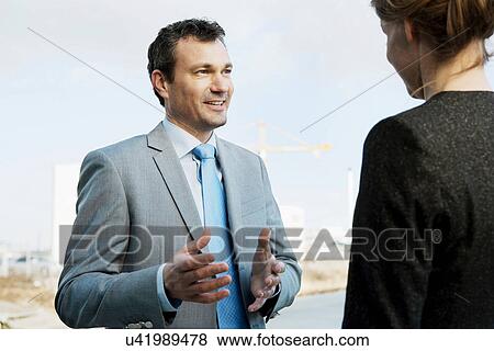 Stock Photo - Mature businessman speaking to colleague outdoors. Fotosearch
