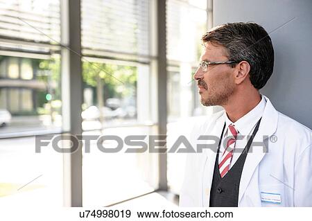 Mature doctor in lab coat looking away View Large Photo Image Stock Photo - Mature doctor in lab coat looking away. Fotosearch