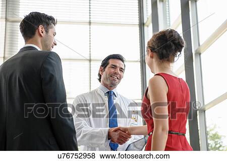 Mature doctor shaking hands with young couple in hospital lobby View Large Photo Image Stock Photo - Mature doctor shaking hands with young couple in hospital lobby. Fotosearch