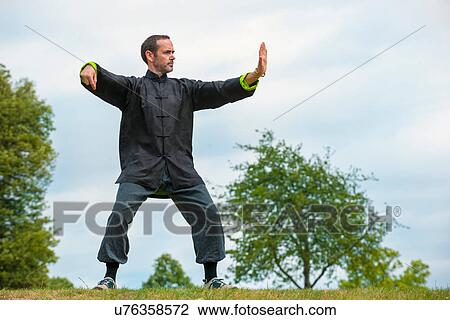 Stock Image - Mature man performing Tai Chi in countryside. Fotosearch