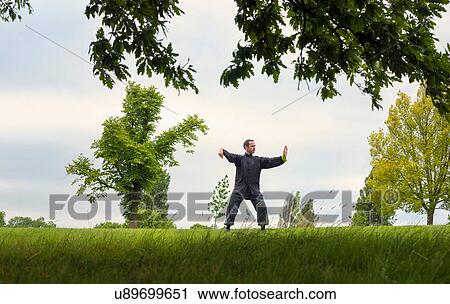 Stock Image - Mature man performing Tai Chi in countryside. Fotosearch