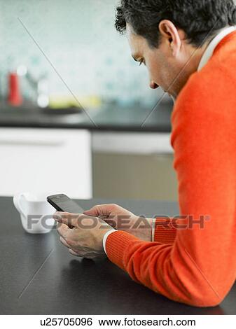 Mature man using cellphone in kitchen View Large Photo Image Stock Photograph - Mature man using cellphone in kitchen. Fotosearch