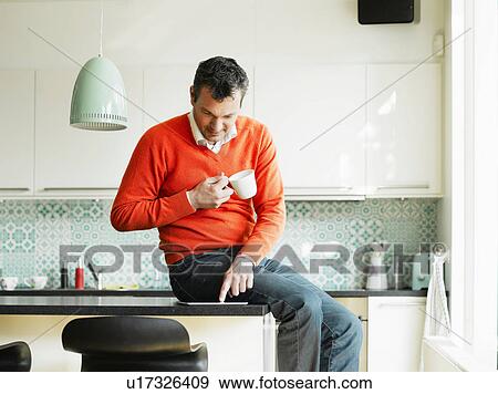 Stock Photo - Mature man using tablet in kitchen. Fotosearch