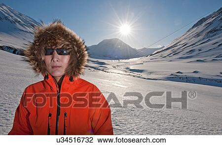 Stock Image - Mature woman in fur lined hood on snow covered mountains, Skidadalur, Dalvik, Iceland. Fotosearch