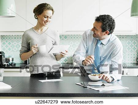 Mid adult woman reading document over breakfast with husband View Large Photo Image Stock Photo - Mid adult woman reading document over breakfast with husband. Fotosearch