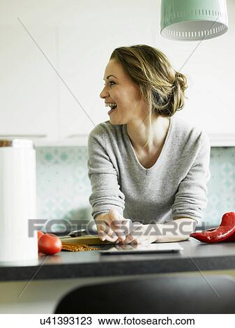 Mid adult woman using digital tablet on kitchen counter, smiling View Large Photo Image Stock Image - Mid adult woman using digital tablet on kitchen counter, smiling. Fotosearch