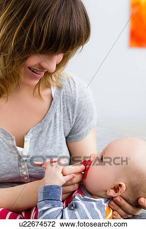 Stock Image - Mother and baby son with pacifier in mouth. Fotosearch