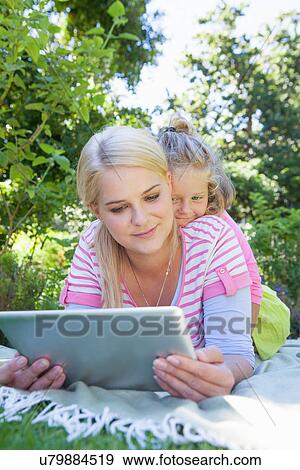 Mother and daughter lying on blanket in garden using digital tablet View Large Photo Image Stock Photo - Mother and daughter lying on blanket in garden using digital tablet. Fotosearch