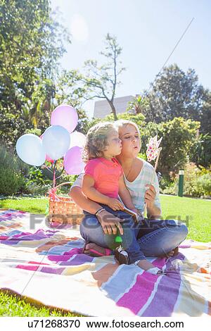 Mother and daughter sitting on blanket in garden with pinwheel View Large Photo Image Stock Image - Mother and daughter sitting on blanket in garden with pinwheel. Fotosearch