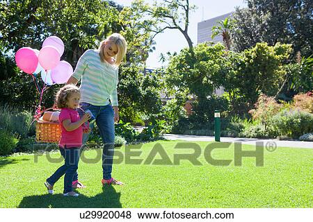 Mother and daughter walking in garden with basket of balloons View Large Photo Image Stock Photo - Mother and daughter walking in garden with basket of balloons. Fotosearch