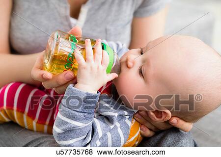 Stock Photo - Mother feeding baby son with bottle. Fotosearch