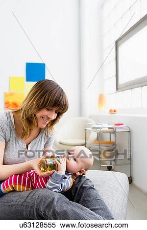 Stock Photography - Mother feeding baby son with bottle. Fotosearch