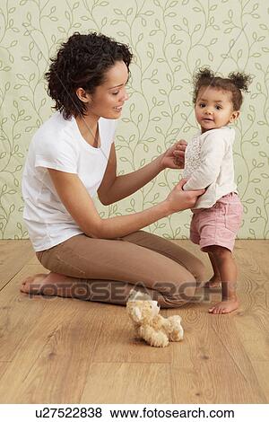 Stock Photo - Mother holding baby girl taking first steps. Fotosearch