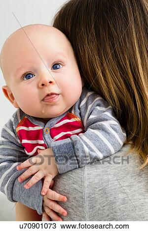 Mother holding baby son over shoulder, dribbling View Large Photo Image Stock Image - Mother holding baby son over shoulder, dribbling. Fotosearch
