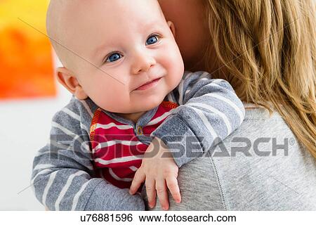 Stock Photograph - Mother holding baby son over shoulder. Fotosearch