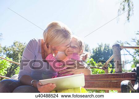 Mother holding laptop and hugging daughter View Large Photo Image Picture - Mother holding laptop and hugging daughter. Fotosearch