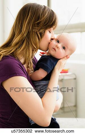 Mother kissing baby son on cheek View Large Photo Image Stock Image - Mother kissing baby son on cheek. Fotosearch