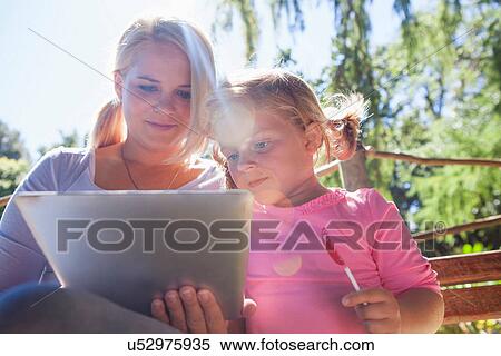 Mother using laptop, girl with lollipop View Large Photo Image Stock Photography - Mother using laptop, girl with lollipop. Fotosearch
