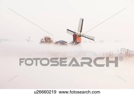 Stock Photo - Old fashioned windmill in misty landscape. Fotosearch