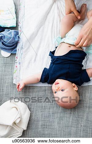 Stock Photograph - Person changing baby boy's nappy, overhead view. Fotosearch