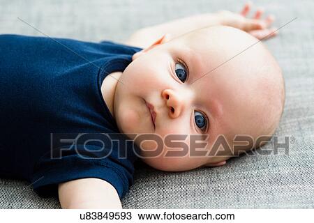 Stock Image - Portrait of baby boy lying on back, close up. Fotosearch