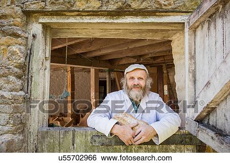 Portrait of man looking through windmill door holding bread View Large Photo Image Stock Photograph - Portrait of man looking through windmill door holding bread. Fotosearch