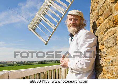 Stock Image - Portrait of man outside windmill. Fotosearch