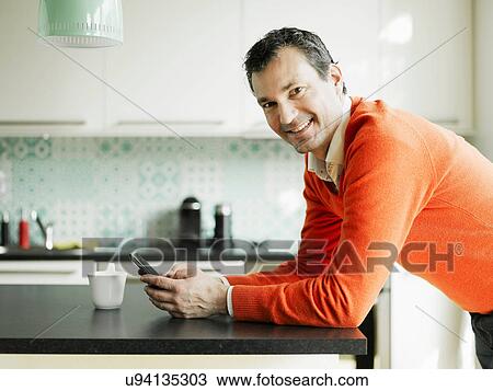 Portrait of mature man using cellphone in kitchen View Large Photo Image Stock Image - Portrait of mature man using cellphone in kitchen. Fotosearch