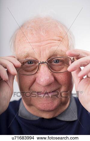Picture - Portrait of senior man adjusting glasses, studio shot. Fotosearch