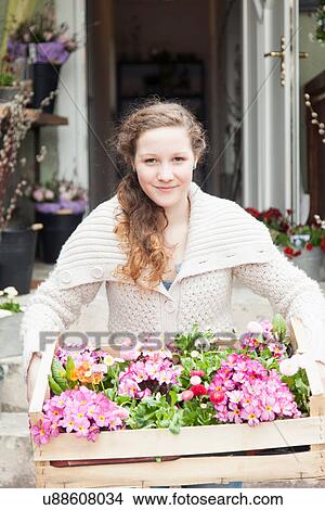 Picture - Portrait of teenage girl carrying crate of flowers. Fotosearch