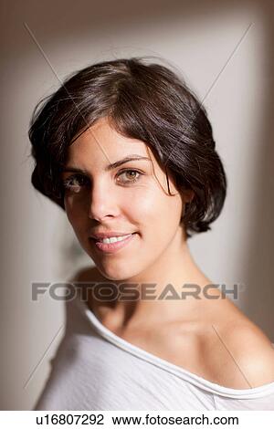 Stock Image - Portrait of woman looking at camera, studio shot. Fotosearch