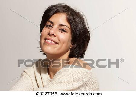 Stock Photograph - Portrait of woman looking at camera, studio shot. Fotosearch