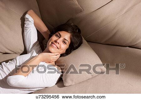 Portrait of woman lying on sofa looking at camera View Large Photo Image Stock Photograph - Portrait of woman lying on sofa looking at camera. Fotosearch