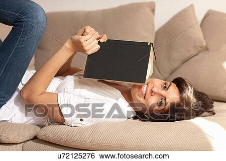Portrait of woman lying on sofa reading book View Large Photo Image Stock Photograph - Portrait of woman lying on sofa reading book. Fotosearch