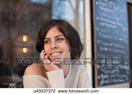Stock Image - Portrait of woman outside cafe looking away. Fotosearch