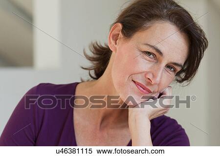 Stock Photography - Portrait of woman wearing purple top, hand on chin. Fotosearch