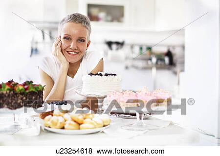 Stock Photo - Portrait of woman with selection of hand made cakes. Fotosearch